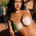 A woman wearing a green bandeau bikini top with a vintage gold ring detail, sitting poolside.