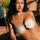 A woman wearing a green bandeau bikini top with a vintage gold ring detail, sitting poolside.