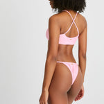 Model wears pink bikini with a cross over back