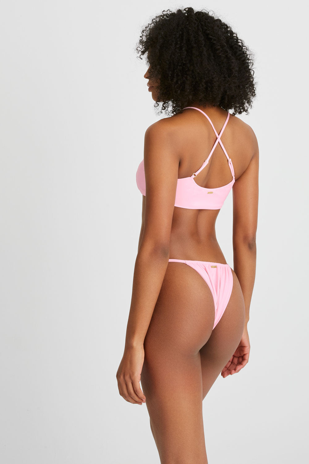 Model wears pink bikini with a cross over back
